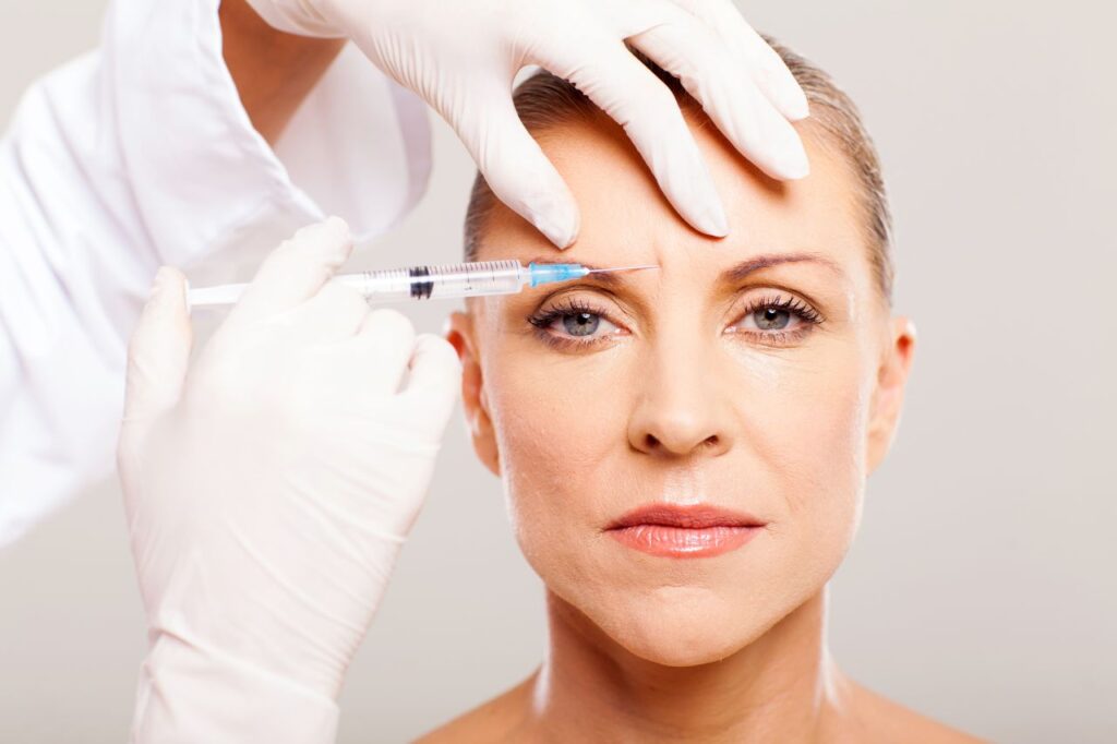 cosmetic surgeon giving face lifting injection to mature woman